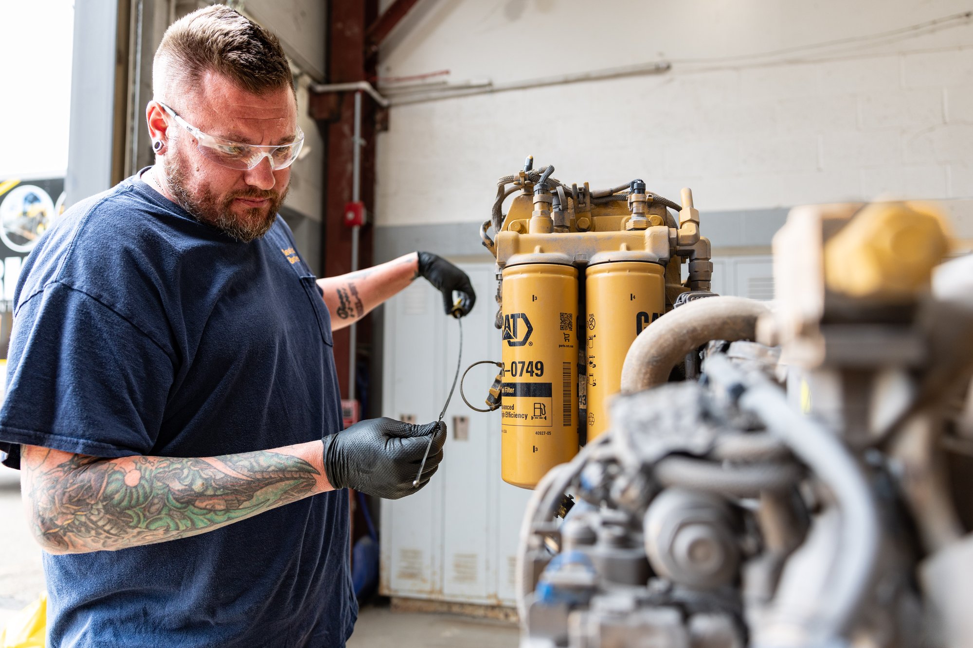 Technician checking engine fluid levels during routine maintenance on equipment.